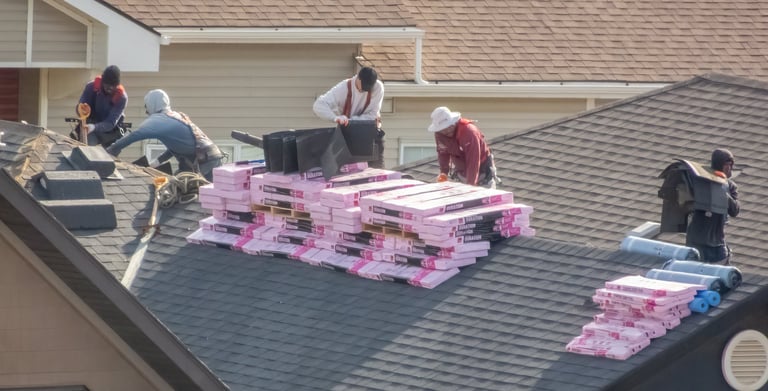 Roofers installing shingles on a residential roof